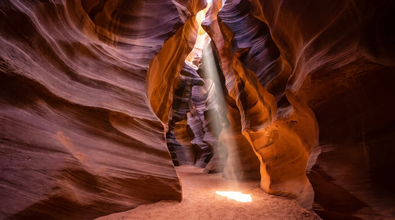 Interior of a narrow sandstone slot canyon with smooth flowing curved walls glowing orange and gold, a single shaft of midday sunlight beaming down onto the sandy floor, Upper Antelope Canyon Navajo Nation Arizona, ultrarealistic photograph representative of the region