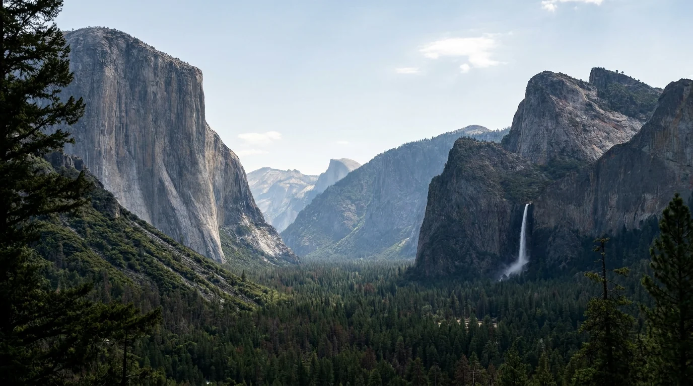 A classic wide view into a granite valley framed by forest, a sheer cliff wall on the left, a tall thin waterfall on the right and a rounded dome in the far center under soft light, Tunnel View Yosemite California, ultrarealistic photograph representative of the region